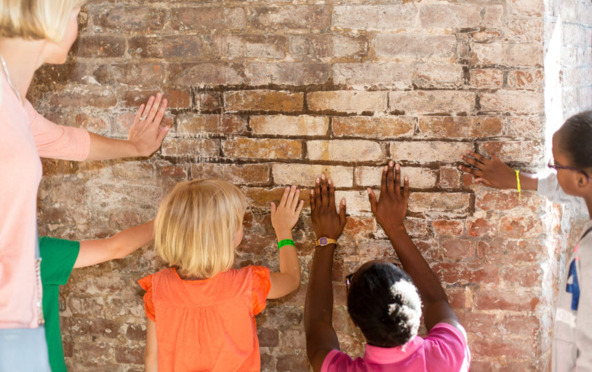 Children curiously touching the bricks of the Charterhouse