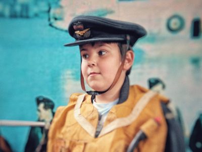 A young boy wearing an RAF uniform worn by aircrew in the 1940s.