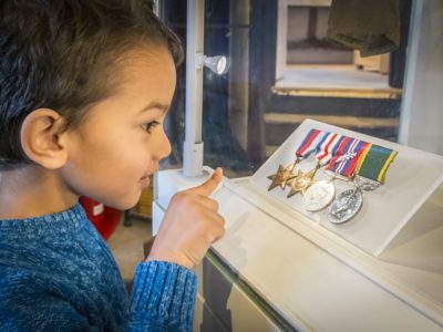 A young boy looking attentively at world war two medals.