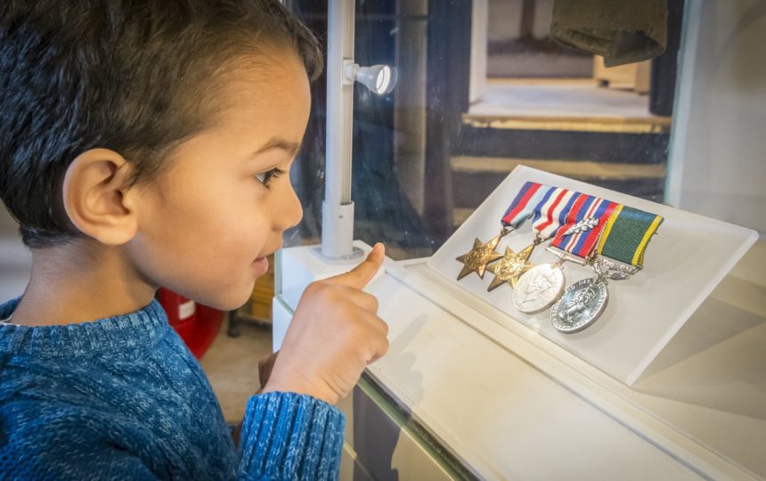 A young boy looking attentively at world war two medals.