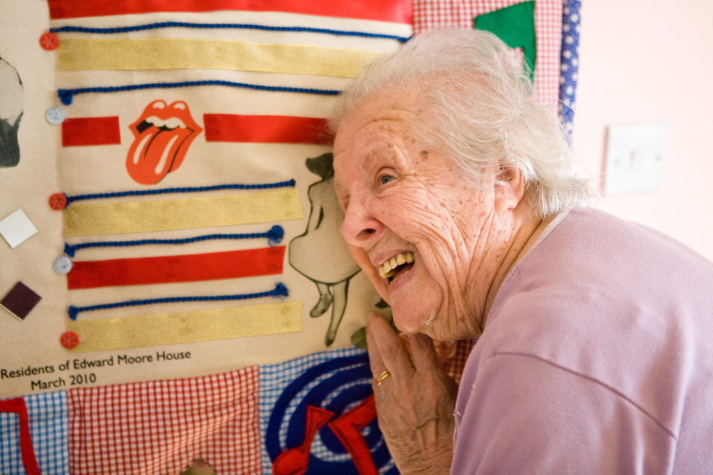 An older woman interacting with a story quilt.